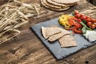 Crispy whole grain crackers with bell peppers, cherry tomatoes and mozzarella on slate