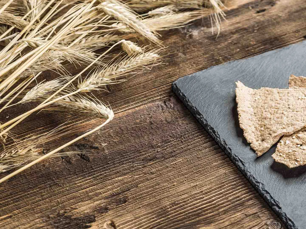 Cracker integrali croccanti con peperoni, pomodori ciliegia e mozzarella su lastra di ardesia