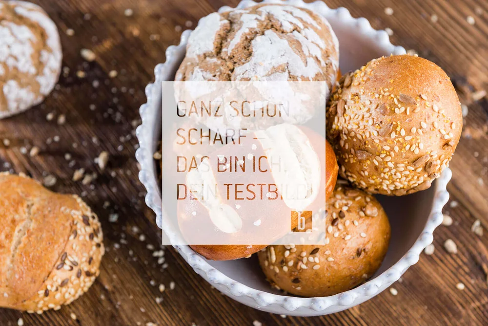 Verschiedene Brötchen mit Körnern in einer weißen Schale auf Holzuntergrund