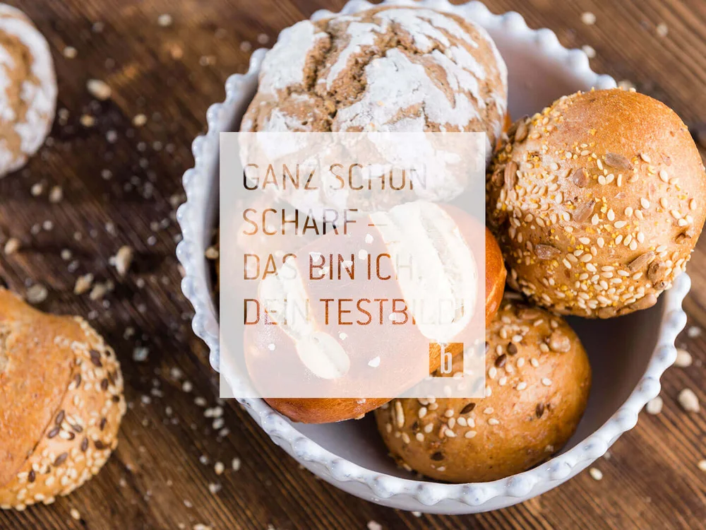 Verschiedene Brötchen mit Körnern in einer weißen Schale auf Holzuntergrund