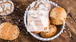 Assorted seeded bread rolls in a white bowl on wooden surface