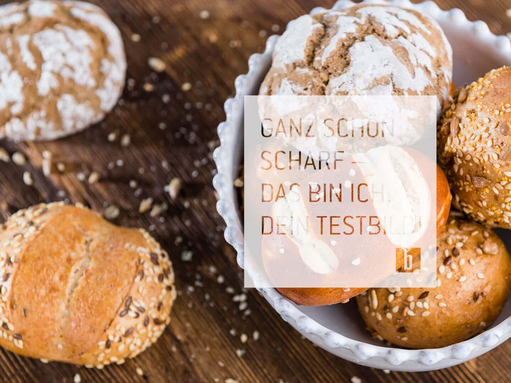 Verschiedene Brötchen mit Körnern in einer weißen Schale auf Holzuntergrund