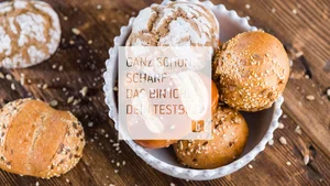 Verschiedene Brötchen mit Körnern in einer weißen Schale auf Holzuntergrund